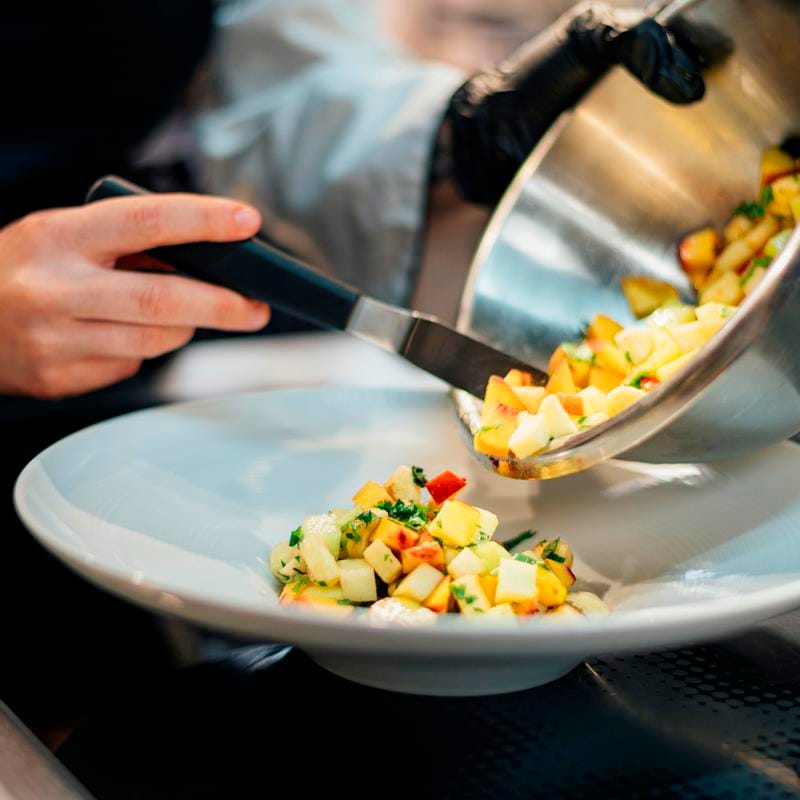 Restaurantes climatizados y con suministro de agua caliente . Confía en Silvan Gas imagen emplatando comida desde un wok. Cocinado con gas